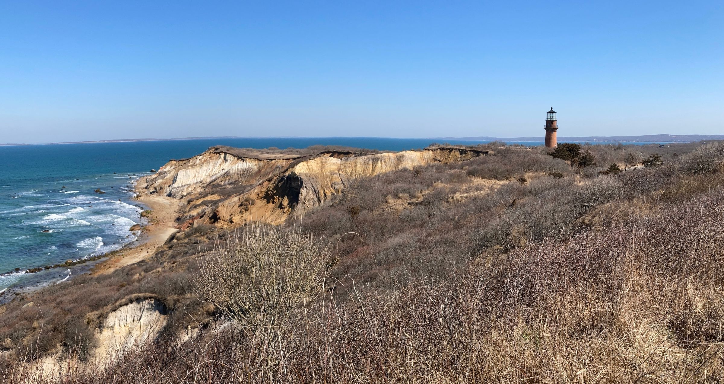 The clay cliffs at Aquinnah on Martha's Vineyard, with Gay Head Light standing on the headland above the water.